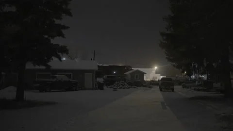 Train slowly passing by small town yard covered in snow at night Stock Footage 225417401