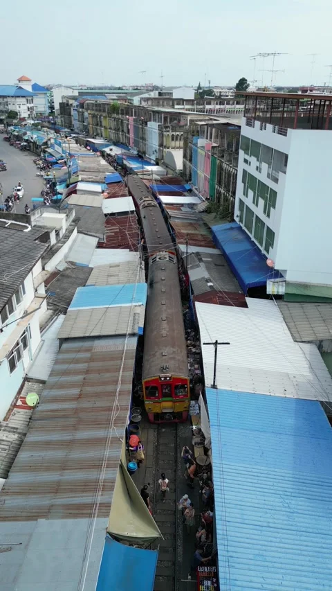 Train Slowly Passing Through Maeklong Railway Market in Samut Songkhram, Video stock 335588721
