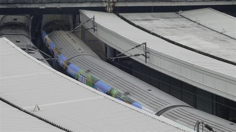 Train snakes past stationary train in station - London, UK from above. Stock Footage 93210116