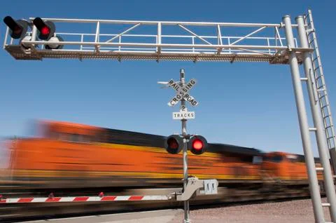 Train speeding by railroad crossing Stock Photos