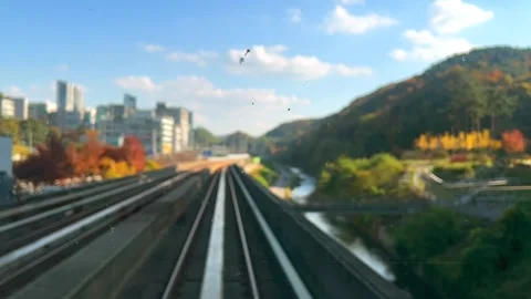 Train through autumn park surrounded by forested hills, river, and city skyline Stock Footage 318657550