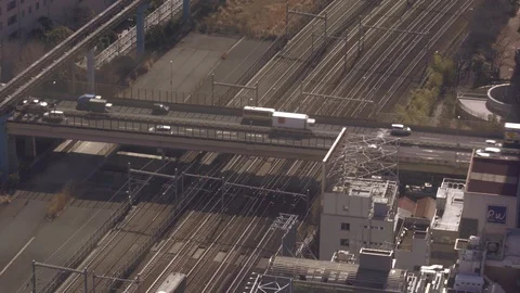 Train in Tokyo passing under a busy motorway bridge Stock Footage 88200198