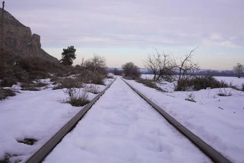 Train track with snow on its surface, in a winter exterior landscape Stock Photos