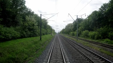 Train tracks curving through lush green landscape under cloudy sky Stock Footage 336924104