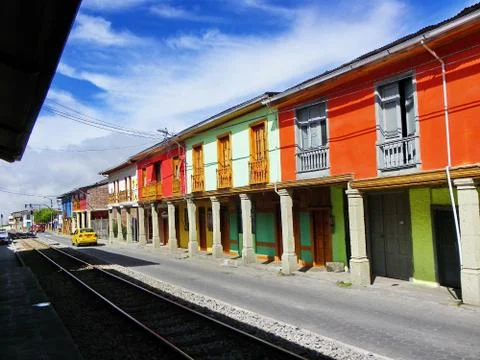 Train tracks going through the town along the colorful buildings Stock Photos