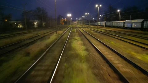 Train tracks illuminated by overhead lights at dusk, signals in the distance Stock Footage 323184092