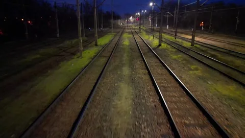 Train tracks illuminated by overhead lights at dusk, showcasing a gradual camera Stockbeeldmateriaal 347790438