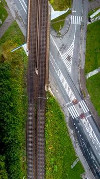 Train tracks intersecting with a modern road in an urban area surrounded by Stock Photos