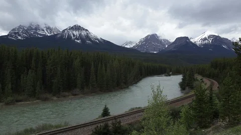 Train tracks run alongside a twisting river bank in Alberta Video stock 90835988