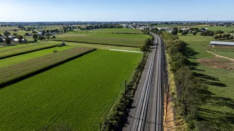 Train Tracks Run Through Fields and Farmland Near a Small Town on a Sunny Day Stock-Fotos