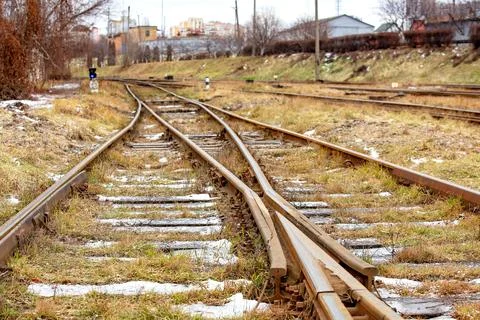 Train tracks run through a grassy area with signs and buildings visible in .. Stock Photos