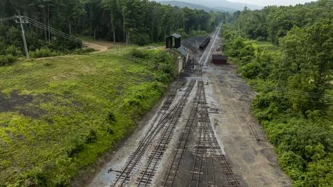 Train Tracks Run Through Green Landscape Near Abandoned Buildings and Fores.. Stock Photos