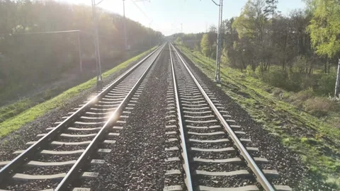Train tracks stretch into the distance through a lush green landscape Stockbeeldmateriaal 347786221