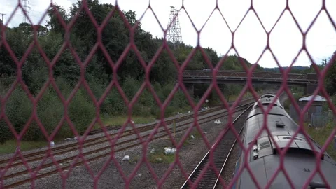 Train on tracks through view of fence bridge Stock Footage 160763826