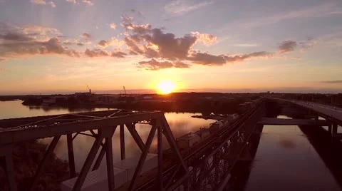 Train traveling across a bridge at sunset Stock Footage