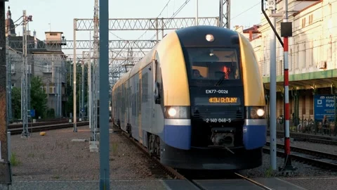 Train traveling down train tracks next to tall building with clock on it. Stock Footage 245098149