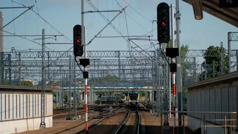 Train traveling down train tracks next to train station with red light. Stock Footage 245098501