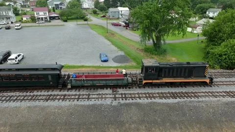 A train travels on tracks next to a small town. People work on the train and Stock Footage 338058553