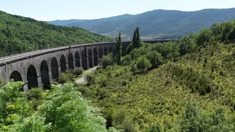 Train viaduct curving through green valley Stock Footage 321954031
