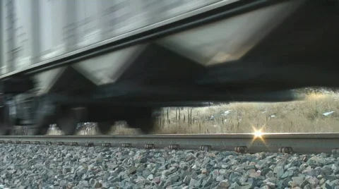 Train wheels speed by as sun reflects off of rails Stock Footage