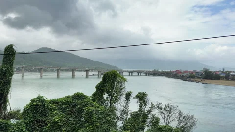 Train-window view of a broad river bridge near a coastal town in central Видео 333673191