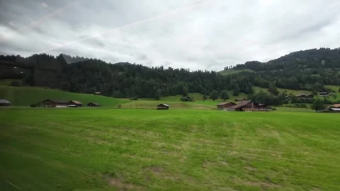 Train Window View of Green Alpine Pasture and Chalets Stock Footage 340369182
