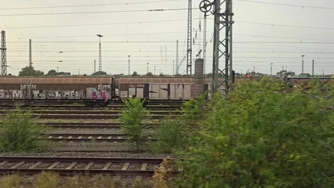 Train window view of railway tracks and freight cars with graffiti during t.. Vídeos de archivo 344673257