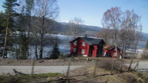 Train Window View of Red Houses and Frozen Lake on Scenic Norway Route in Spring Stock Footage 340357277