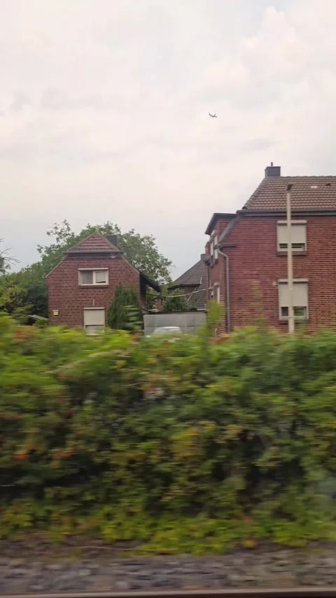 Train window view of suburban houses, an airplane in the sky, and a street .. Stock Footage 344672697