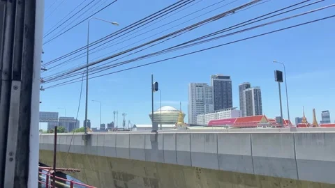 Train window view sunny day. High rise buildings, temples, cars passing by Stock Footage 221680006