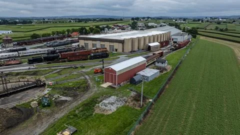 Train Yard and Storage Facility in Rural Area With Green Fields and Cloudy Sk Foto stock