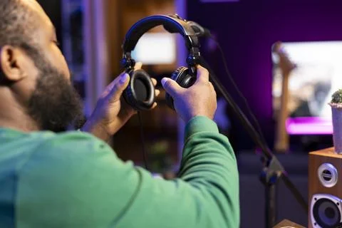 Trained audio technician picking up his headset for a recording session Stock Photos