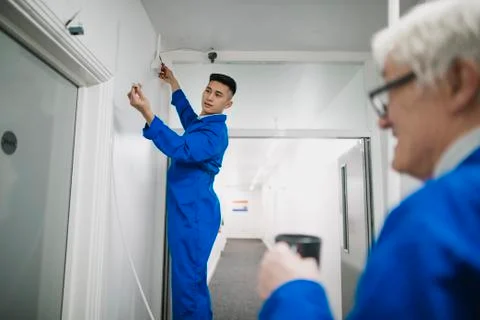 Trainee Electrician Fitting a Security Camera Fotos Stock