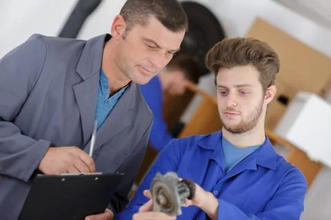 Trainee mechanic identifying part Stock Photos