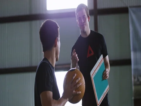 Trainer assisting the athlete to hold the ball 動画素材 77490894