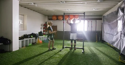 Trainer assisting man with pull-up at gym 動画素材 77324320