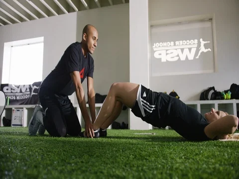 Trainer assisting woman with abdominal exercise at gym Stock Footage 77345705
