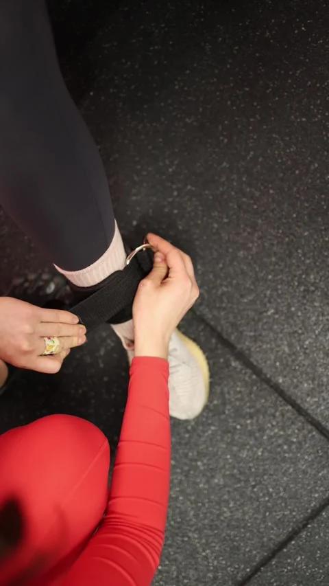 Trainer attaches ankle strap Stock Footage 337956730
