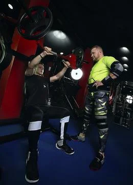 Trainer coaches and explains how to do exercises in the gym bodybuilding fitness Stock Photos
