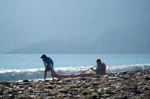 Trainer dragging a kayaker over the wave into the sea in Turkey Foto stock