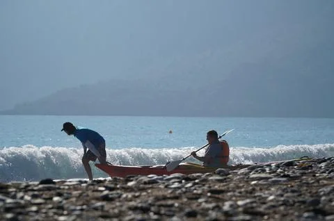 Trainer dragging a kayaker over the wave into the sea Stock Photos
