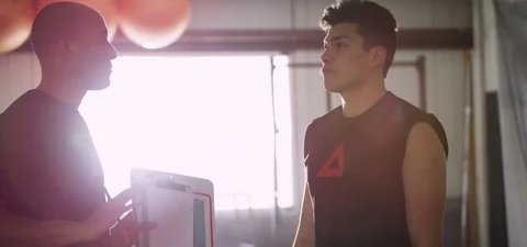 Trainer explaining about exercise to man in fitness studio 動画素材 77329202