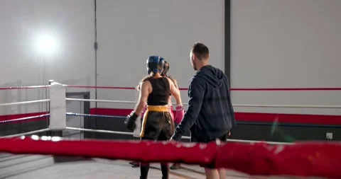 Trainer fixing rope in ring, fitting pads, guiding sparring for training, black Stock Footage 340986374
