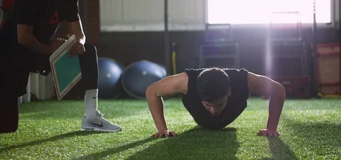 Trainer giving high-five to man after completing his push-up at fitness studio Stock Footage 78203565