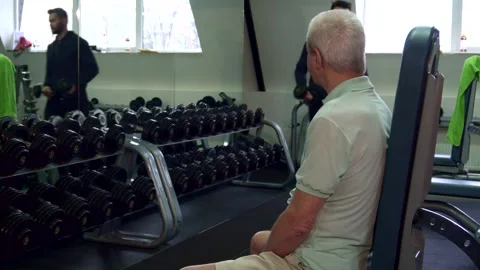 Trainer hands dumbbells to senior client in a gym Stock Footage 311510641
