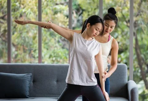 Trainer help young lady to stretching arm and make balance. They in living .. Foto stock