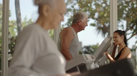 Trainer helping old man and woman exercising in fitness gym Stock Footage 11144235