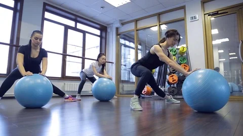 Trainer with her group of women do exercises with blue fitboll in gym Stock Footage 74079344