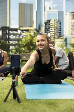 Trainer leading mindful Pilates session on yoga mat while filming with phone Stock Photos