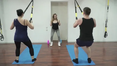 Trainer making squats with the trainees in fitness hall Stock Footage 73546053